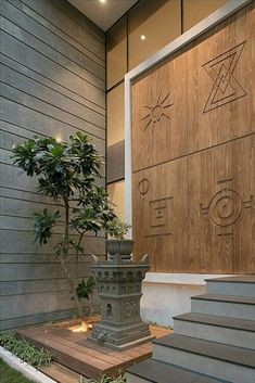 a small bonsai tree in front of a modern house with stairs leading up to it