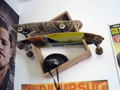 a skateboard mounted to the side of a wall next to a poster and clock