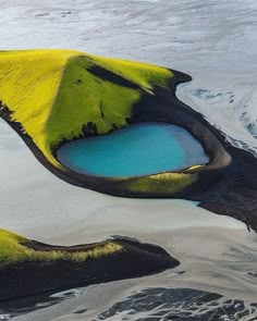 an aerial view of some water and land with yellow algae growing on the rocks in the foreground