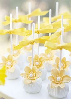 yellow and white cake pops with flowers on them are ready to be served for guests