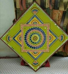 a yellow and blue decorative plate sitting on top of a table next to a pillow