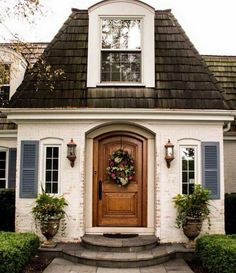 a white house with blue shutters and a wreath on the front door is shown