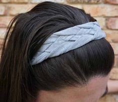 a woman wearing a gray headband with long hair in front of a brick wall