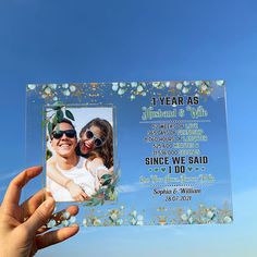 a person holding up a glass photo frame with the words, i year as husband and wife