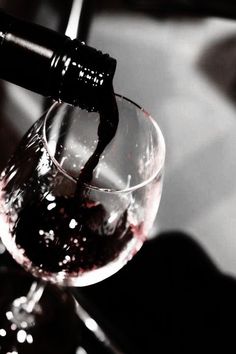 a wine glass being filled with red wine