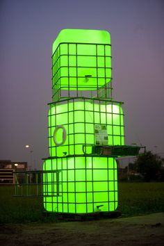 two large green containers sitting on top of each other in front of a building at night