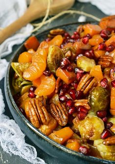 a pan filled with carrots, brussel sprouts and pecans