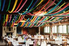 a room filled with lots of tables covered in white tablecloths and colorful streamers