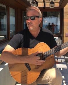 a man is playing an acoustic guitar outside