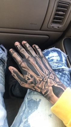 a man's hand with a skeleton tattoo on it sitting in the back seat of a car