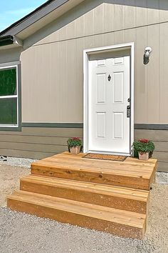 a white door sitting on the side of a wooden steps next to a house with potted plants