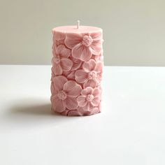 a pink candle that has flowers on it