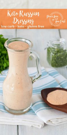 a pitcher filled with dressing sitting on top of a wooden table next to a spoon