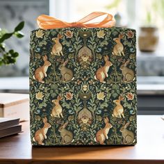 a gift box with an orange bow on it sitting on a table next to books