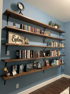 the bookshelves are lined up against the blue wall in this living room with wood flooring