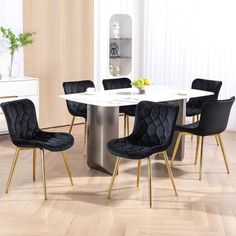 a dining room table with black chairs and a white marble top in front of a wooden floor