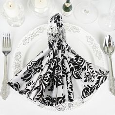 a white plate topped with a black and white napkin next to silver utensils