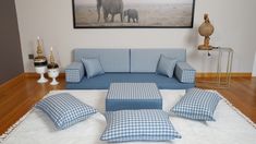 a living room with blue and white furniture on the floor, an elephant painting over the couch