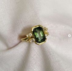 a green ring sitting on top of a white cloth