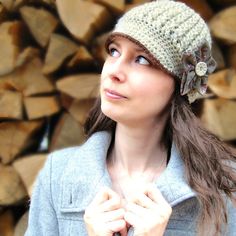 a woman standing in front of a pile of firewood wearing a knitted hat