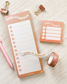 a notepad, pen and some paper clips on a table with other items around it