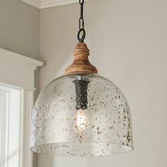 a glass light fixture hanging from a ceiling in a room with white walls and windows