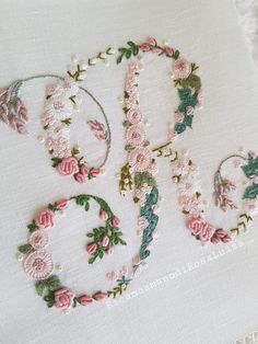 embroidered letters and numbers with pink flowers on white linens, including the letter q