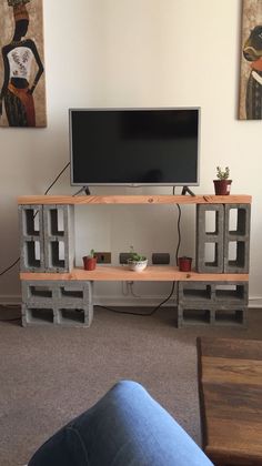 a flat screen tv sitting on top of a wooden shelf next to a blue couch