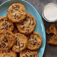 chocolate chip cookies on a blue plate next to a glass of milk