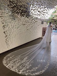 a woman in a wedding dress is standing near a wall with silver foil on it