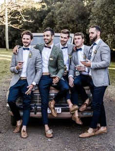 a group of men in suits sitting on the back of a car with their arms around each other