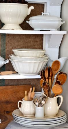 white dishes and utensils are stacked on shelves