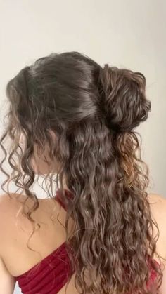 the back of a woman's head with long curly hair in a red dress