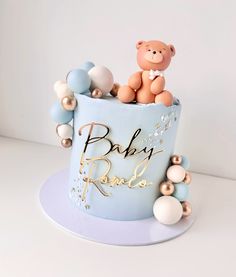 a baby shower cake with a teddy bear on top