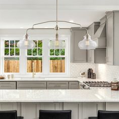 a kitchen with white counter tops and gray cabinets