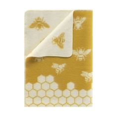 a yellow and white blanket with honeybees printed on the front, in two different colors