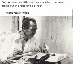 a black and white photo of a man sitting at a desk with a book in front of him