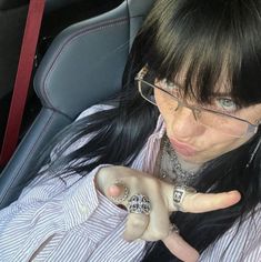 a woman sitting in the back seat of a car pointing to her left with both hands