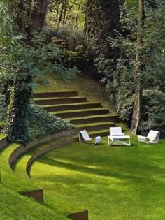 some chairs are sitting on the grass in front of stairs that lead up to trees