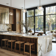 a large kitchen with marble counter tops and wooden stools next to an open window