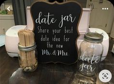 a couple of jars sitting on top of a table next to a chalkboard sign