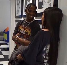 a man and woman standing next to each other in a room with pictures on the wall