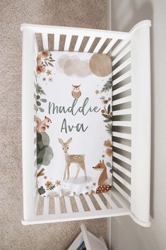 a white crib with a deer and forest scene on the cover that says middle age ava