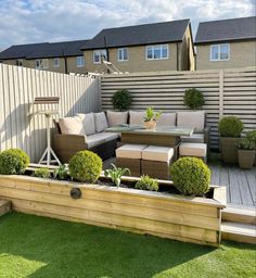 an outdoor living area with couches, tables and potted plants on the grass