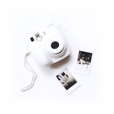 a white polaroid camera sitting on top of a table next to two pictures and a string