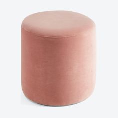 a round pink ottoman sitting on top of a white floor