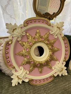 an ornate pink and gold mirror on top of a bed