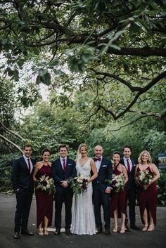 a group of people standing next to each other in front of some trees and bushes