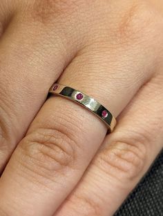 a woman's hand with a ring on it and pink stones in the middle