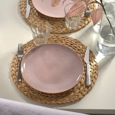 a table set with pink plates and silverware